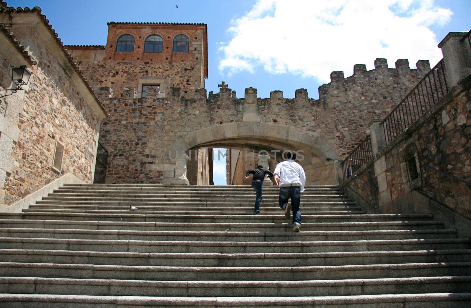Two guys running up the Estrella Arch stairs, at Caceres Old Town