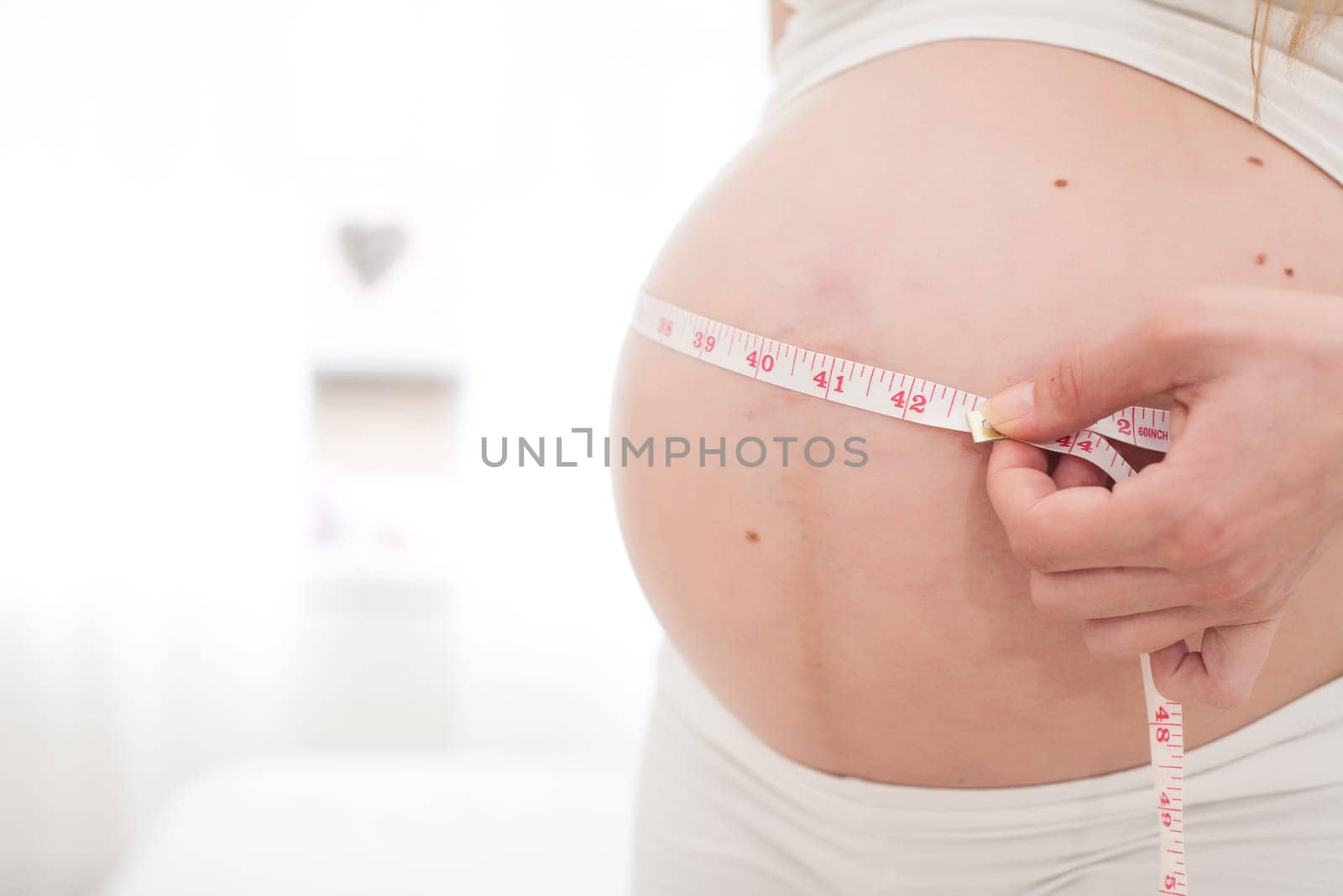 Young new mother is measuring her size of her belly