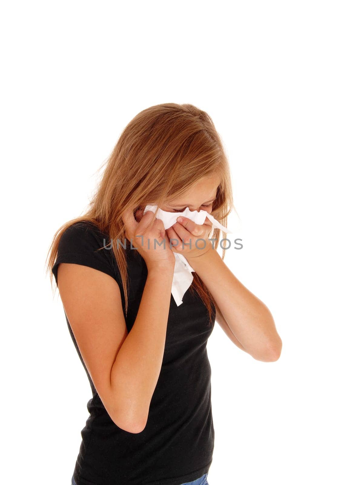 A lovely blond little girl standing in a black sweater blowing her nose,.isolated for white background..