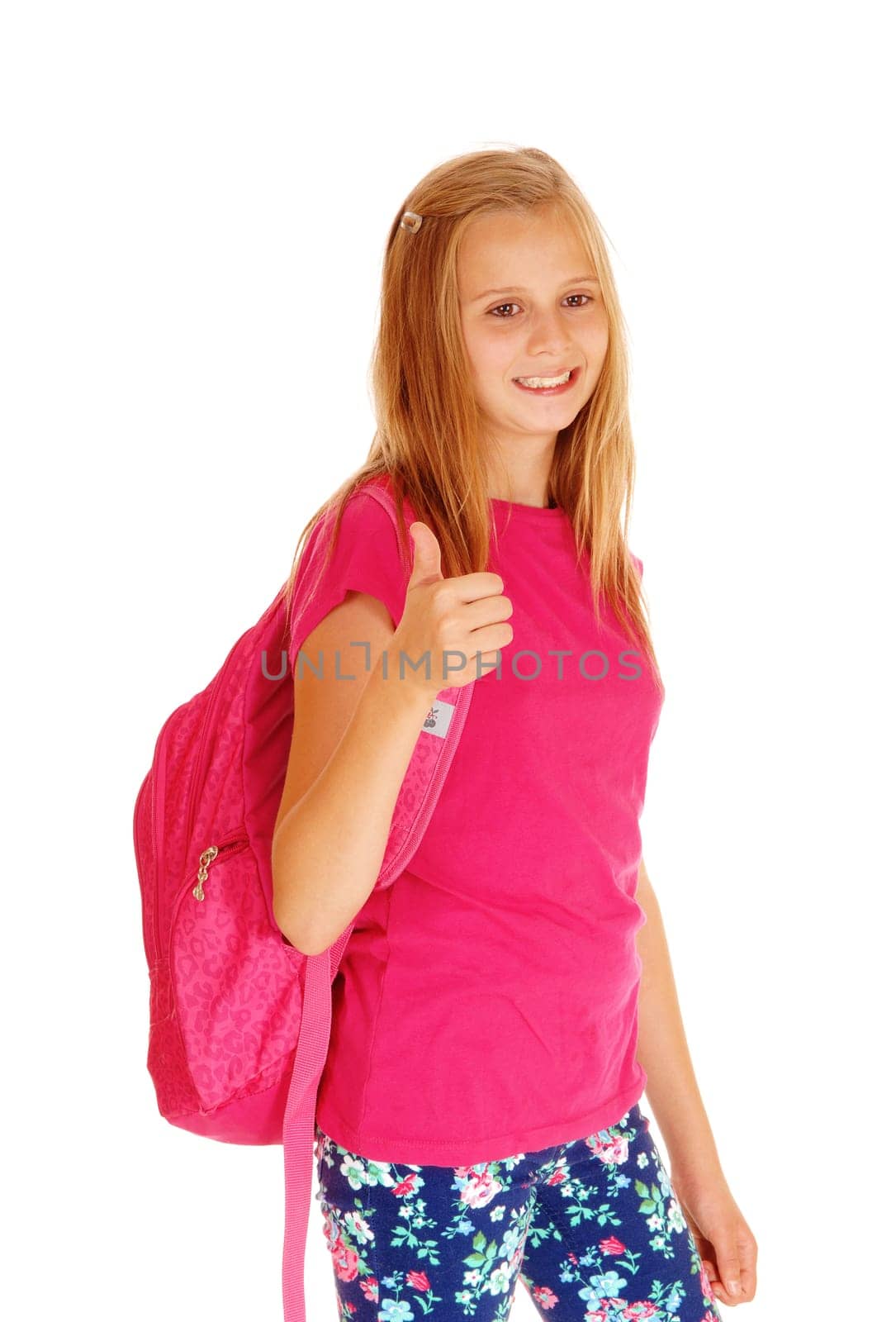 A lovely slim young girl with her backpack on her back standing for white.background, smiling and ready to go to school..