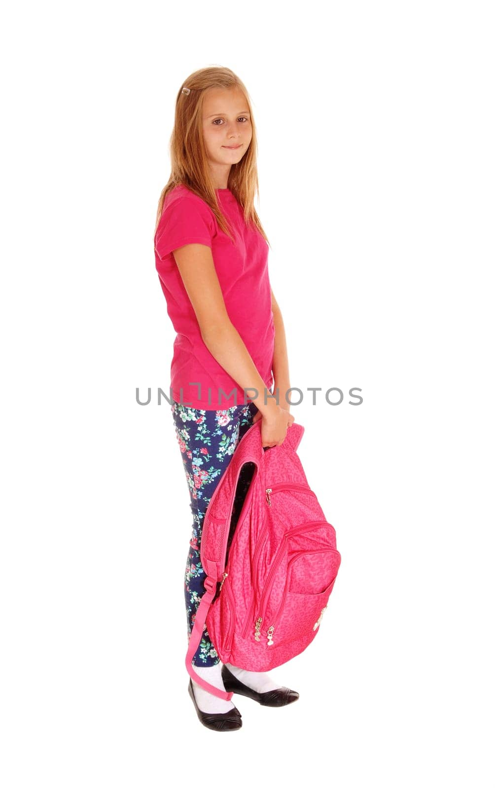 A lovely slim young girl with her backpack in her hand standing for white.background, smiling and ready to go to school..