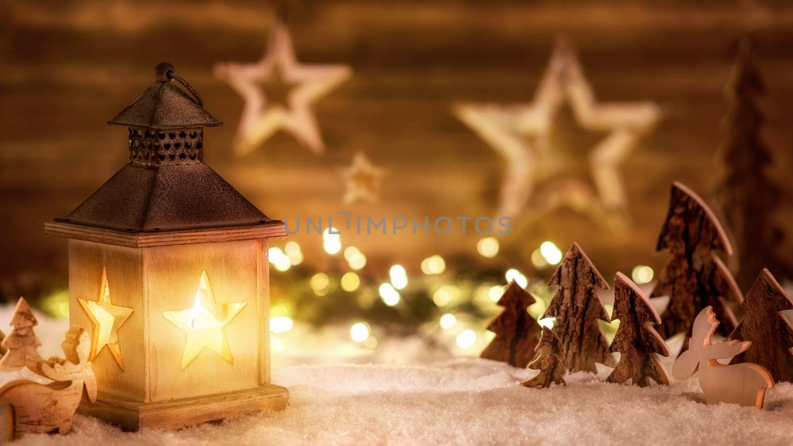 Cozy Christmas arrangement with beautiful wooden ornaments on snow in the warm candlelight of a nice lantern,low-key studio shot
