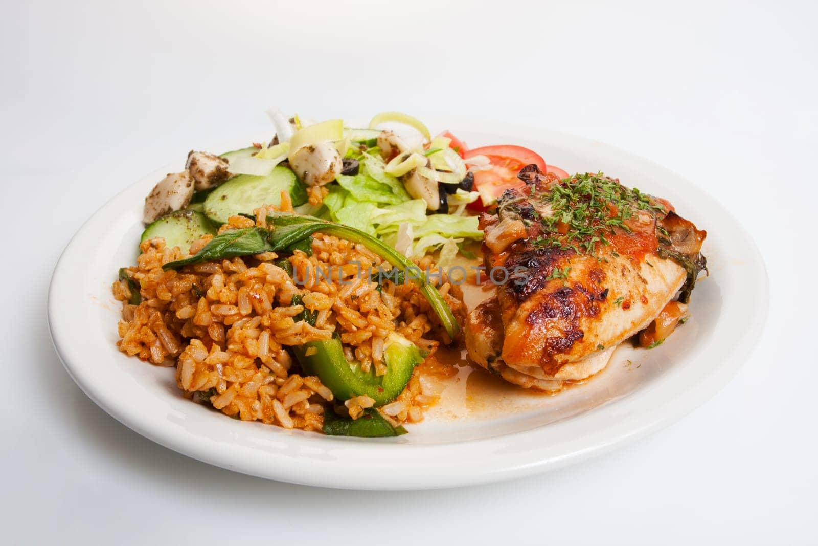 Plate of prepared chicken dinner shot on white with rice and salad