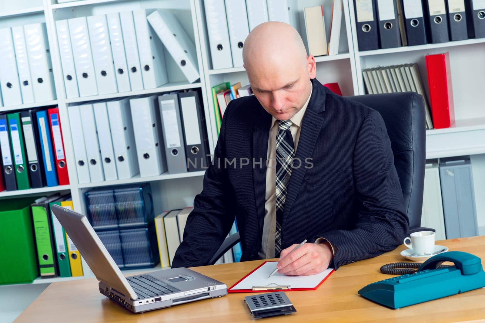 young businessman with bald head in the office is writing