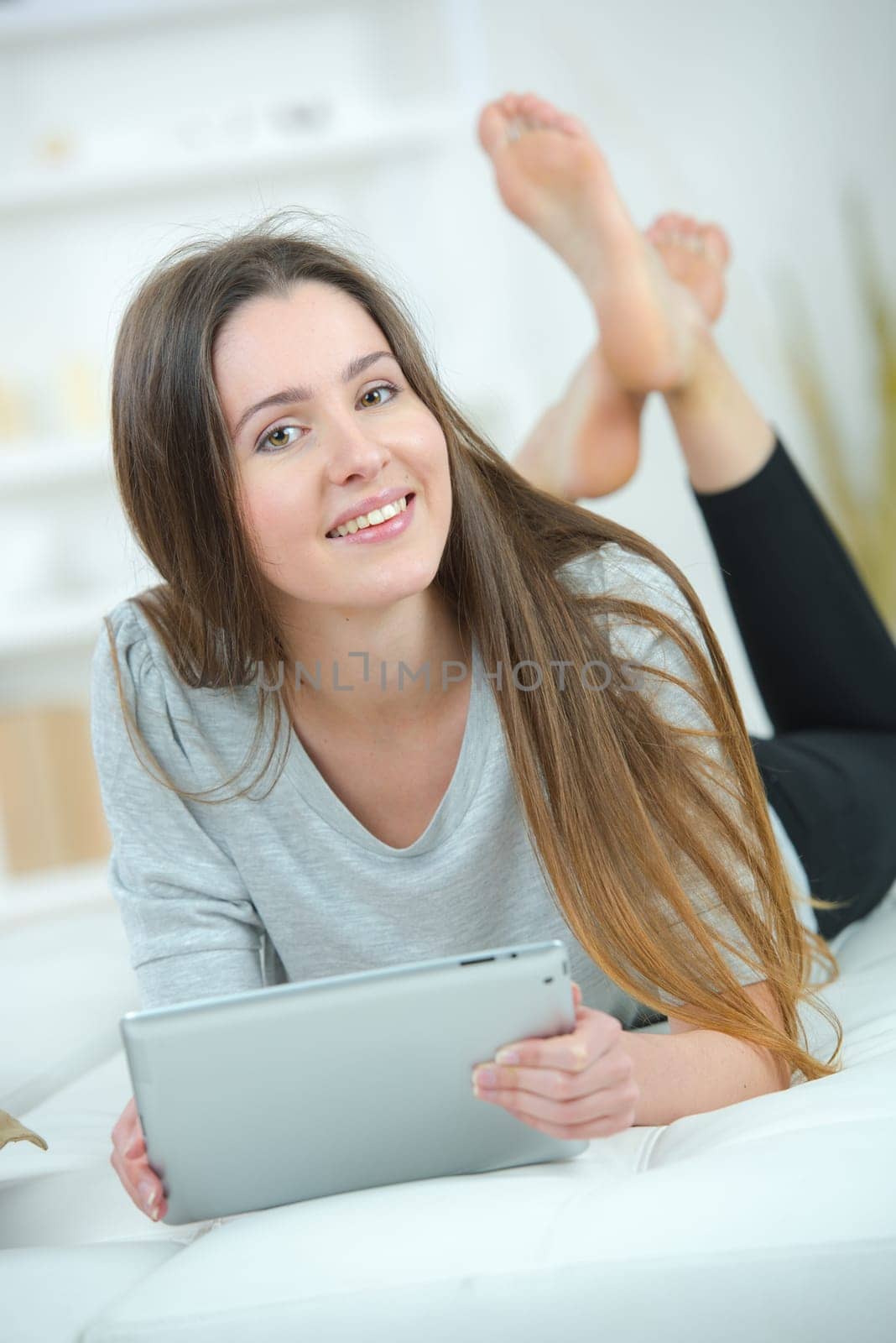 Woman laying on a sofa with her tablet