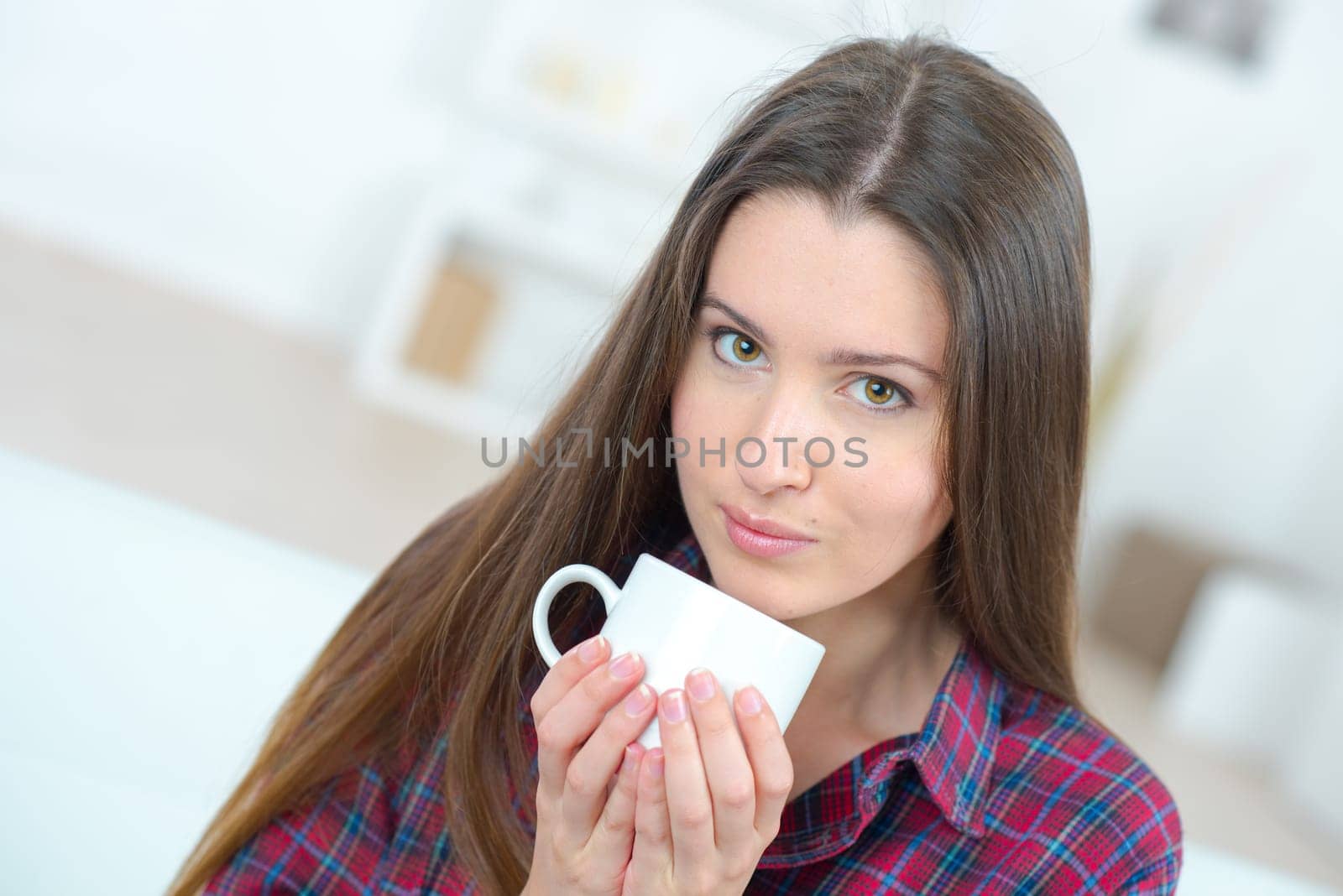 Woman drinking a cup of coffee on the sofa
