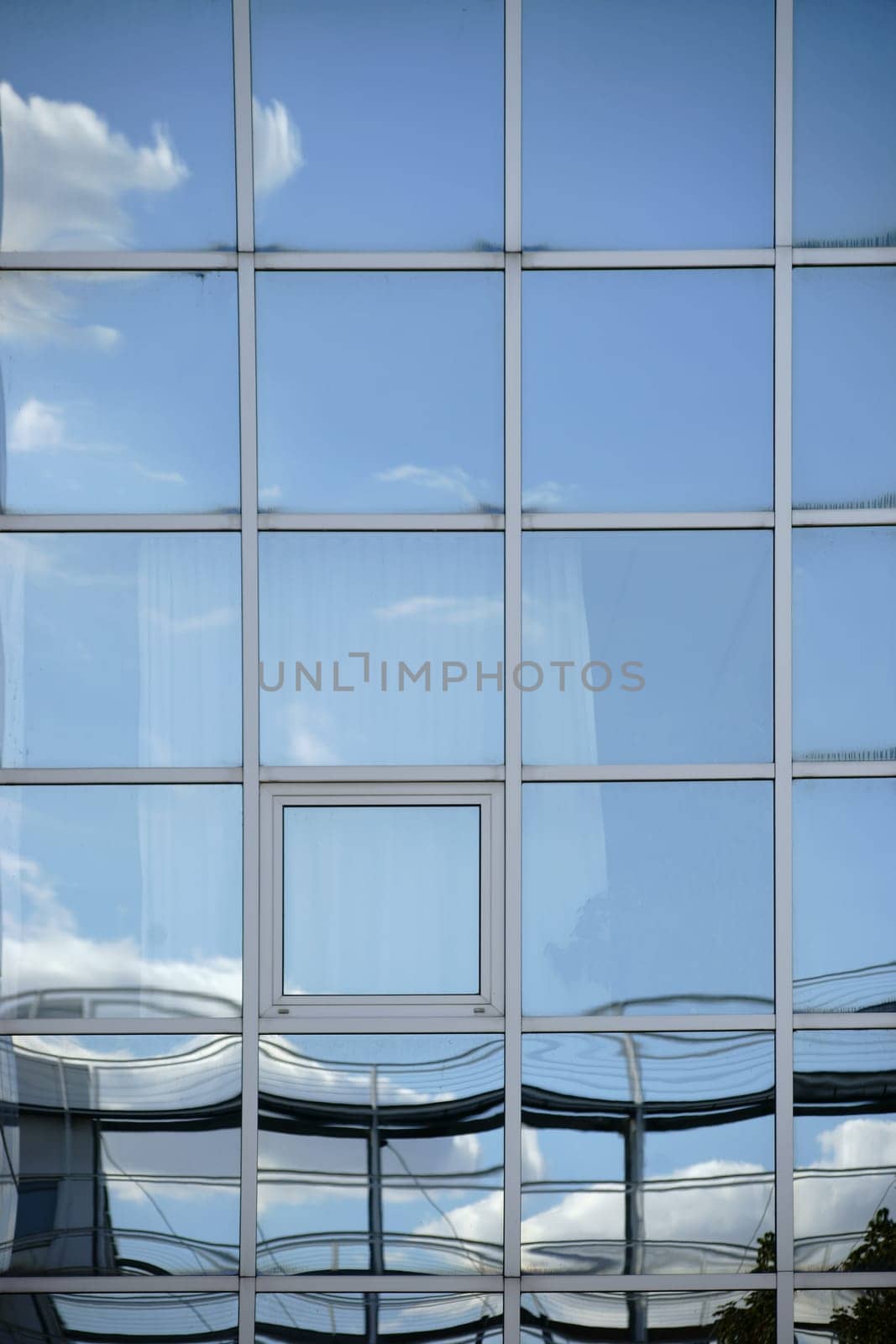 A white cloud and reflections in the windows of a modern facade.