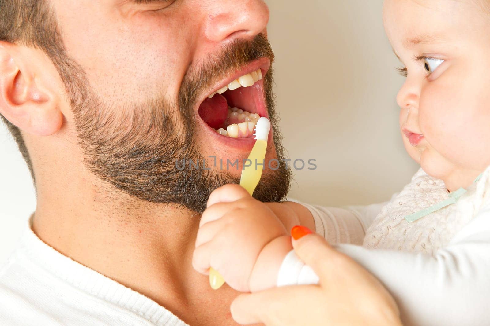 Baby brushes teeth from dad