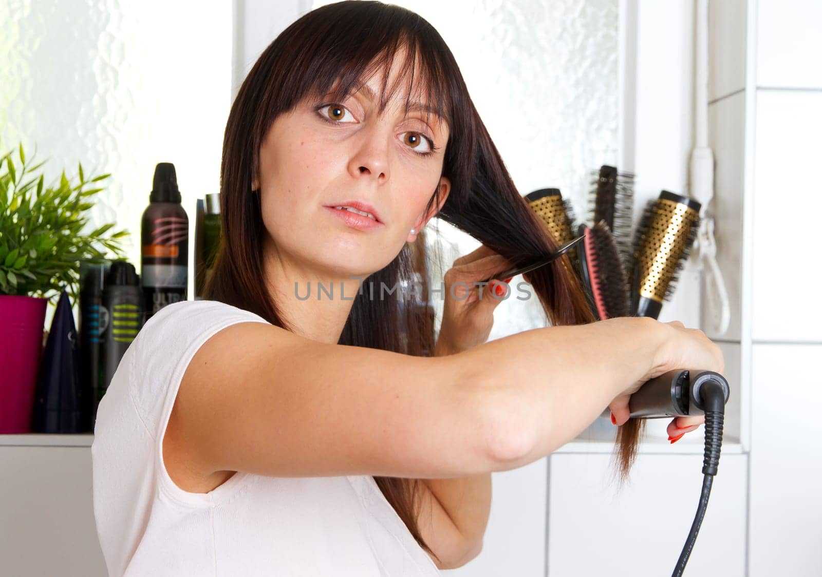 Young woman in the bathroom while smoothing her hair
