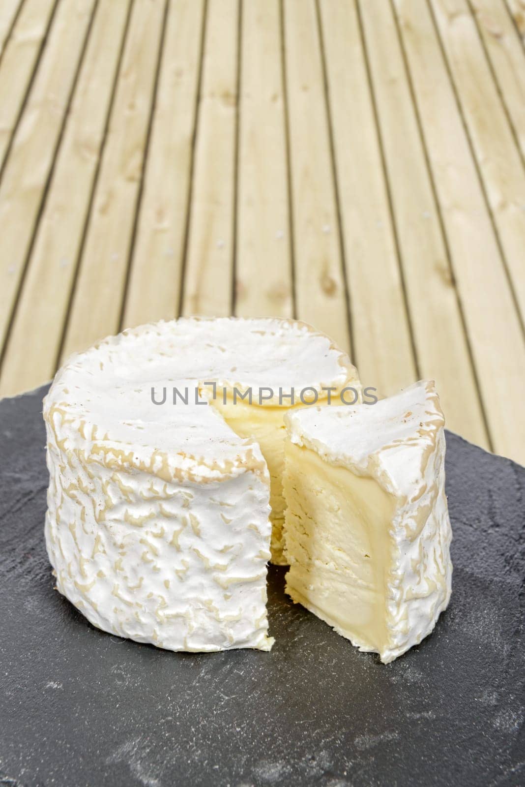 french cheese placed on a black slate, wood in background