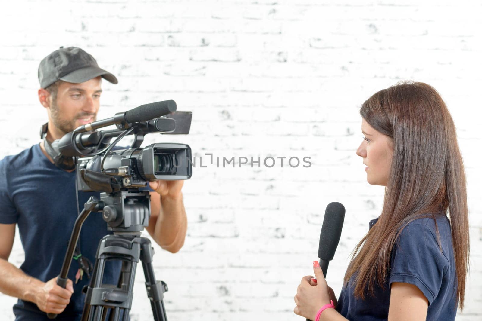 a young woman journalist with a microphone and a cameraman