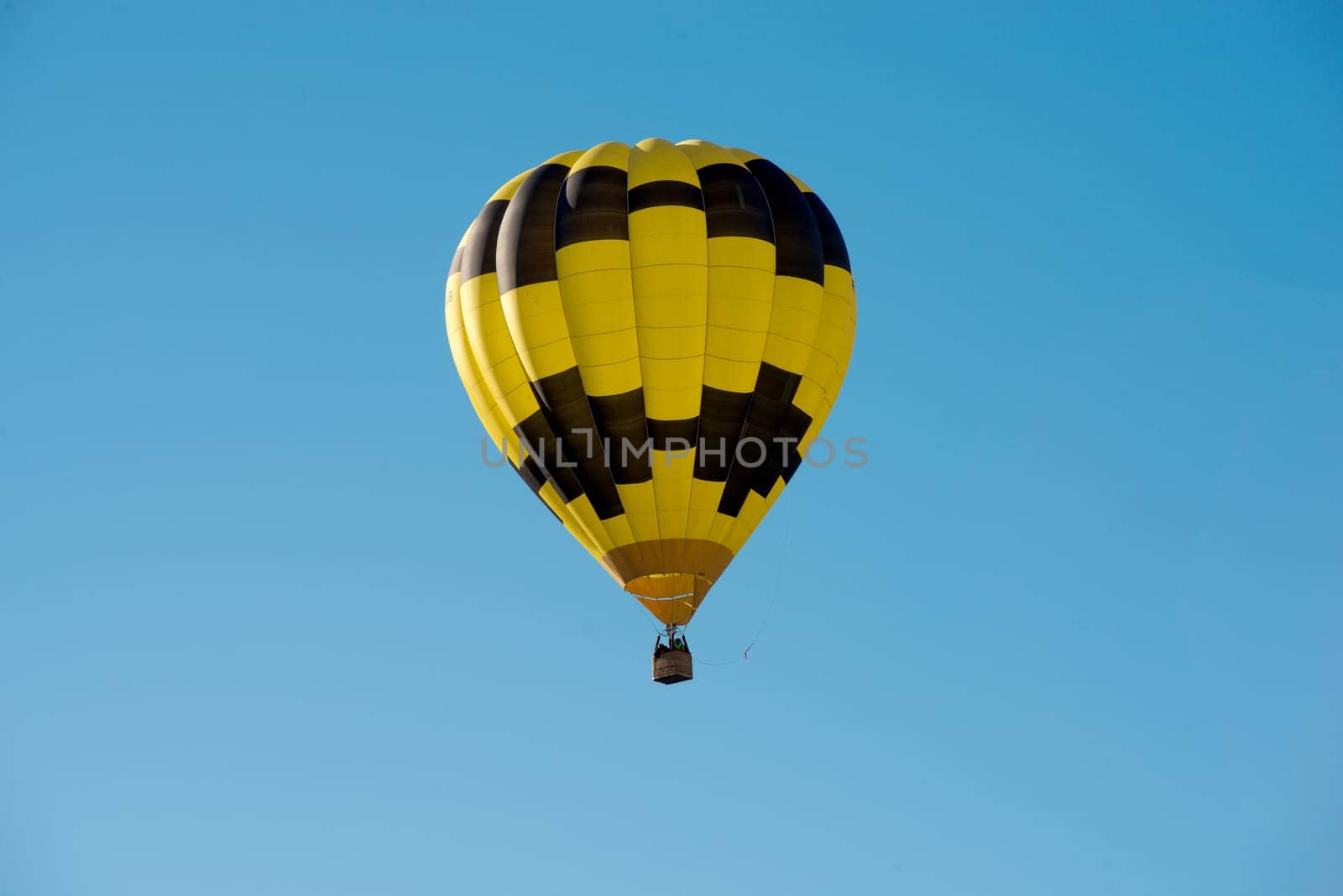 a black and yellow hot air balloon in a blue sky
