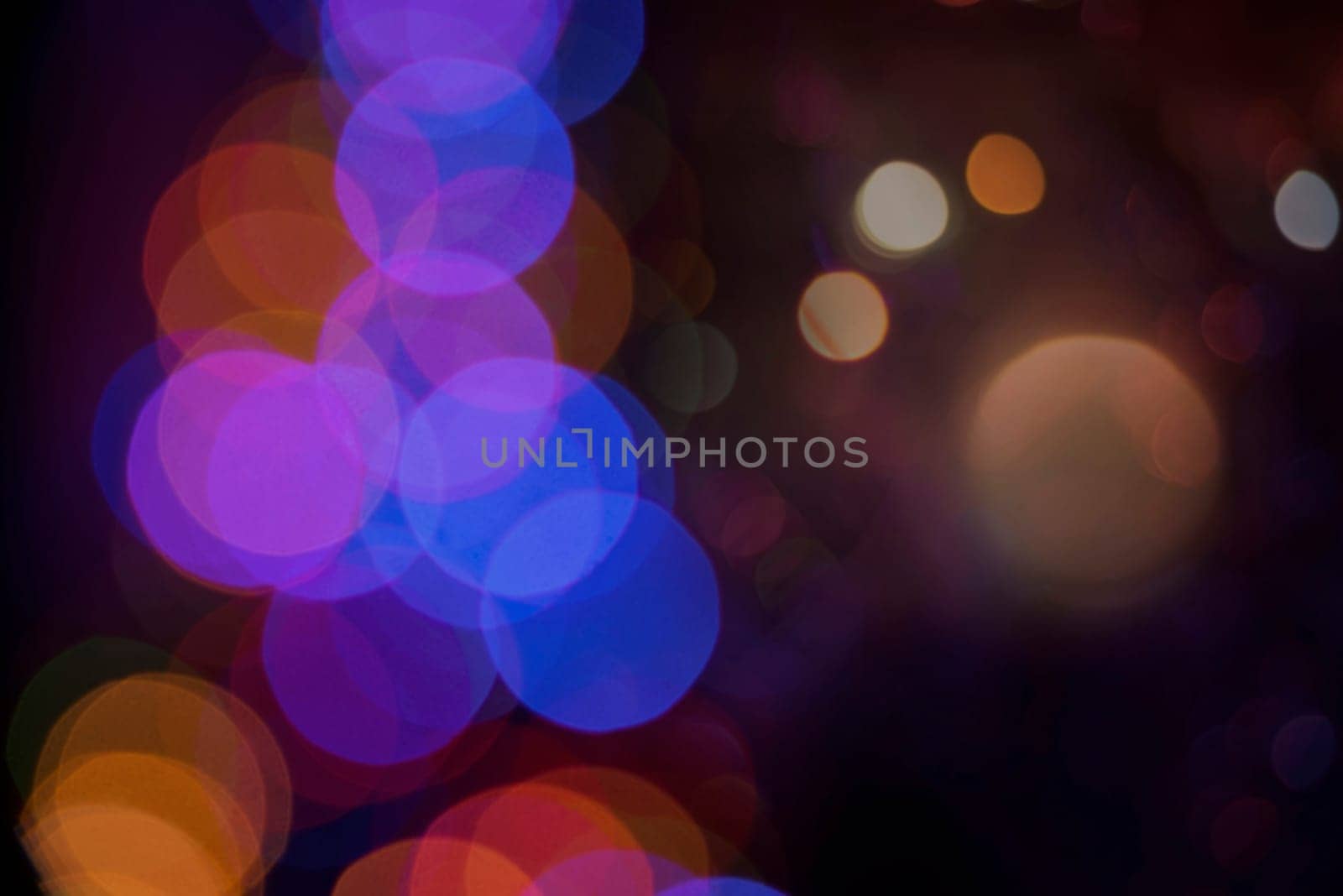 Blur color bokeh lights on dark night time background. Ideal for holiday greeting card, event invitation or web backdrop.