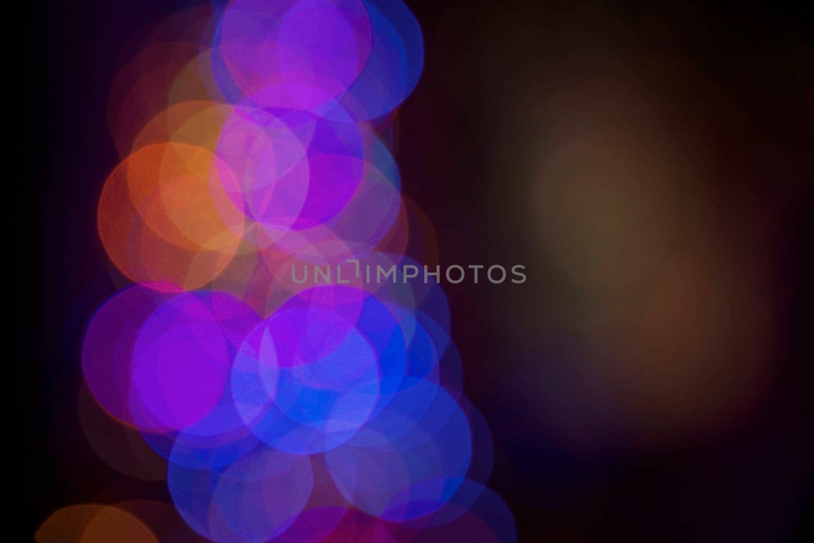 Blur colorful bokeh lights on dark night time background. Ideal for holiday greeting card, event invitation or web backdrop.