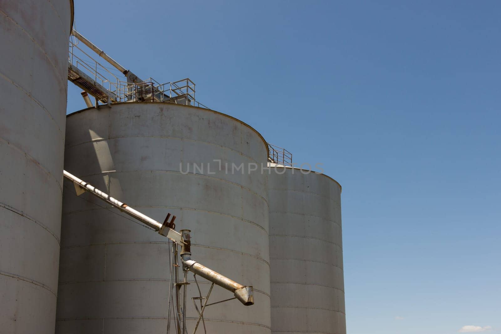 Large steel grain silos with cloudless blue skies.