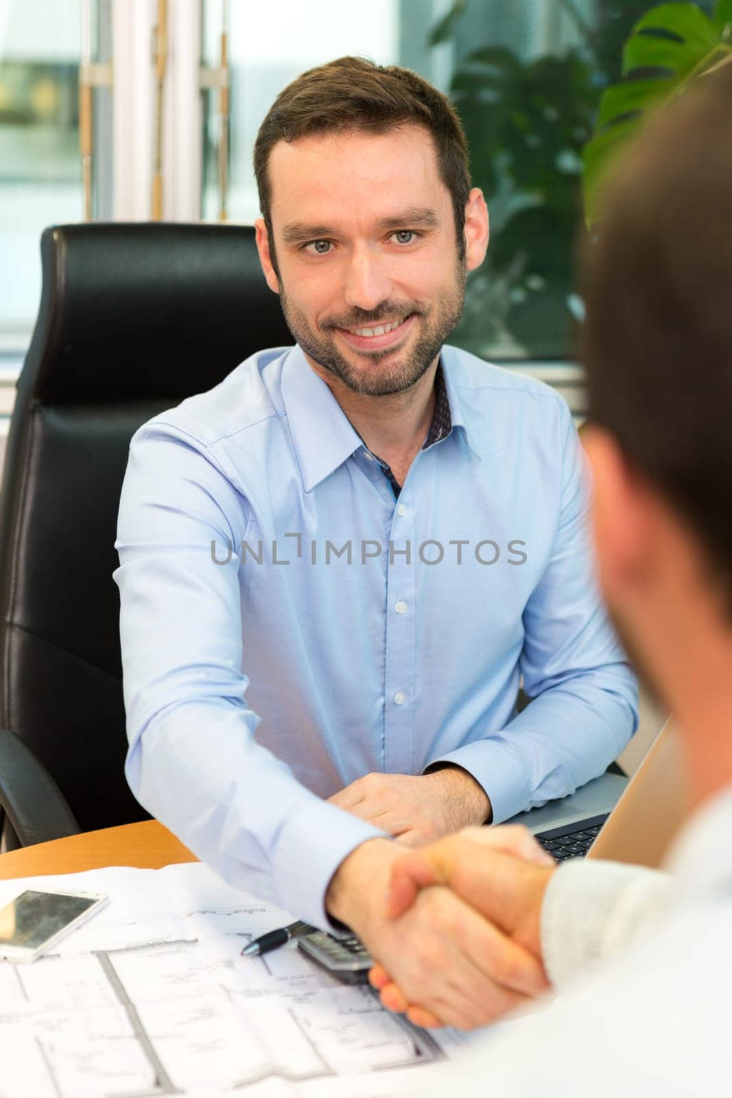 View of a Real estate agent meeting couple at the office