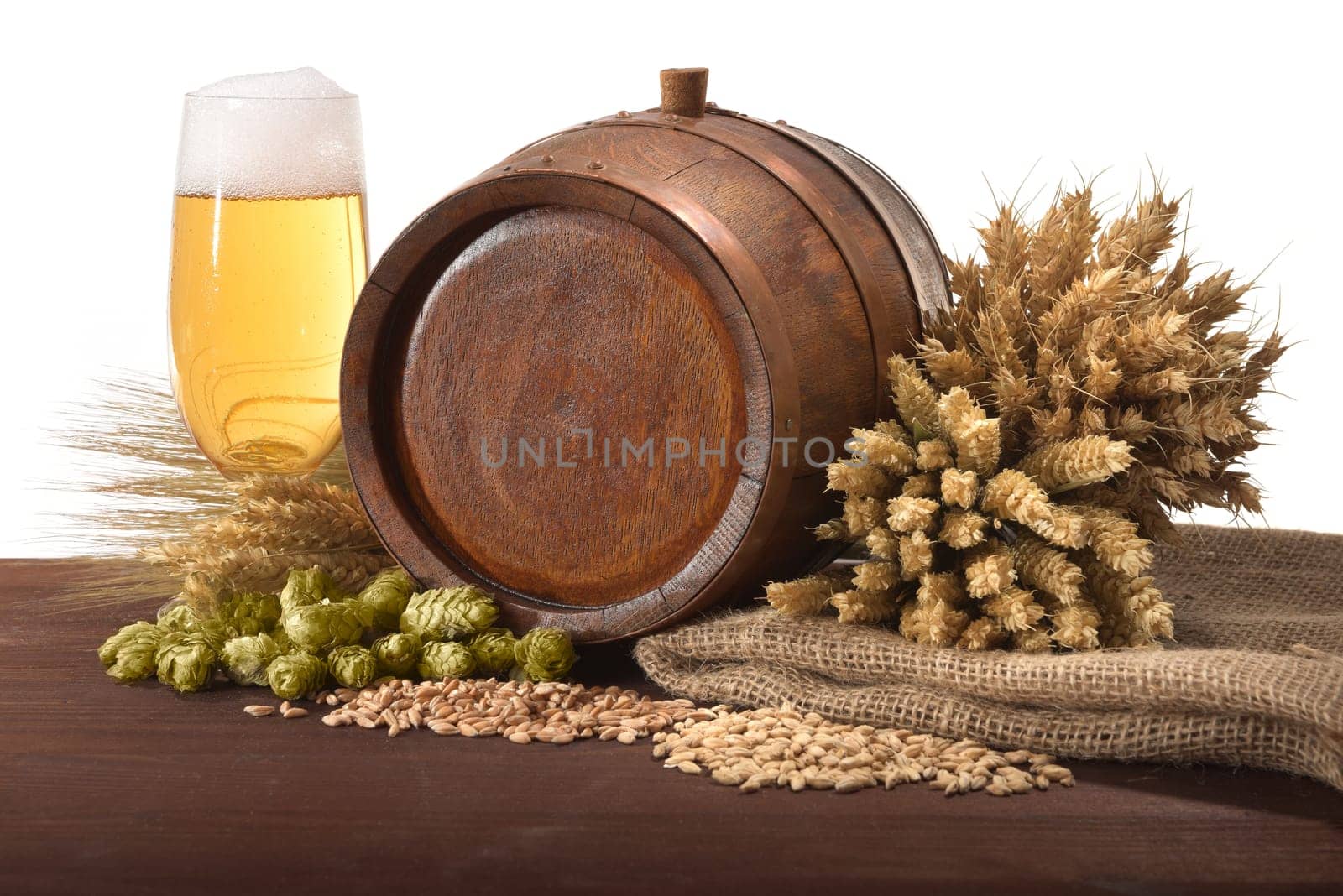Old wooden barrel with beer glass,wheat,barley,hops and malt against a white background