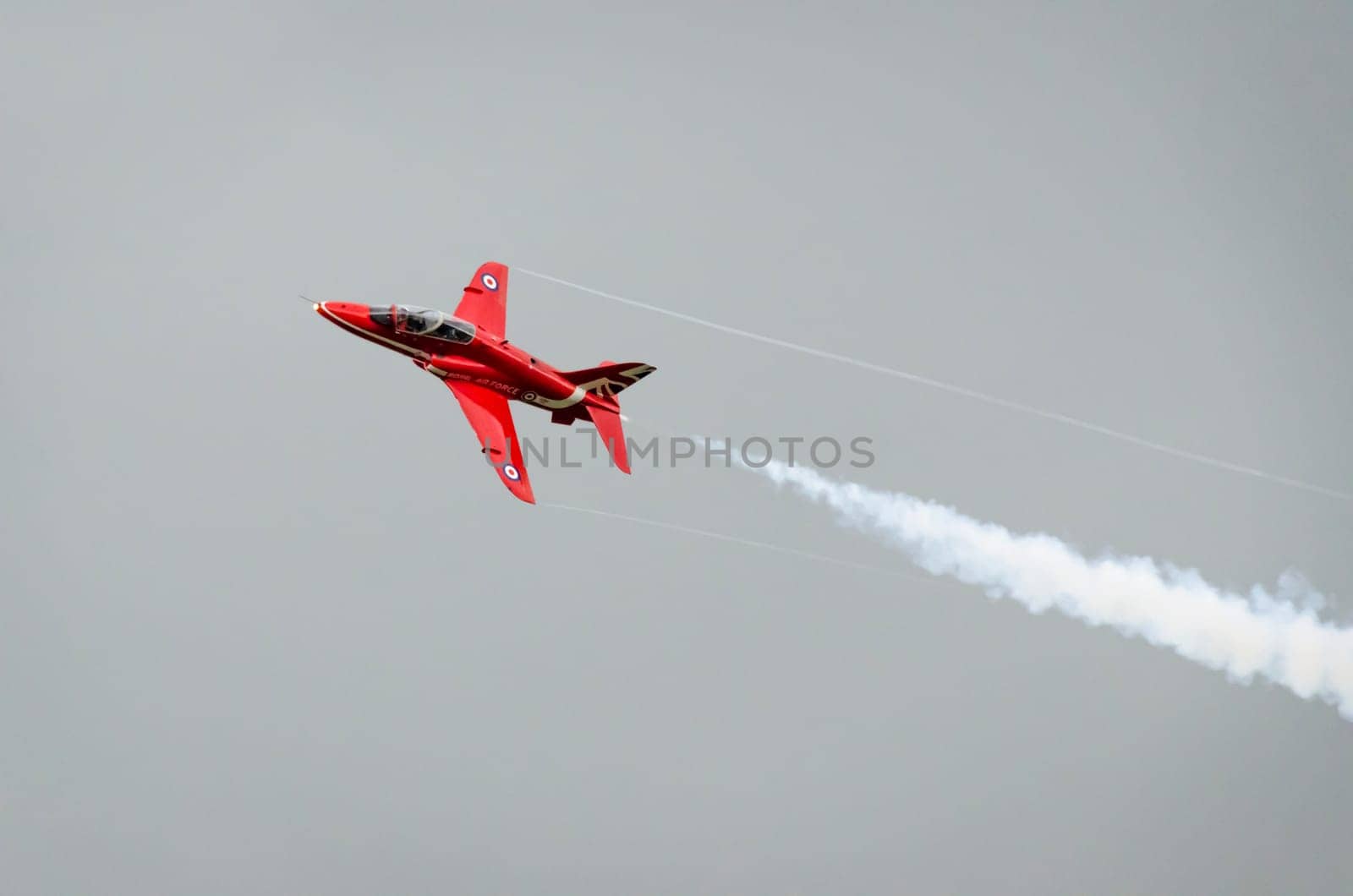 HEADCORN, KENT, ENGLAND - 15 AUGUST 2015: A single Red Arrow aeroplane in flight with white vapour emitting from it's tail end