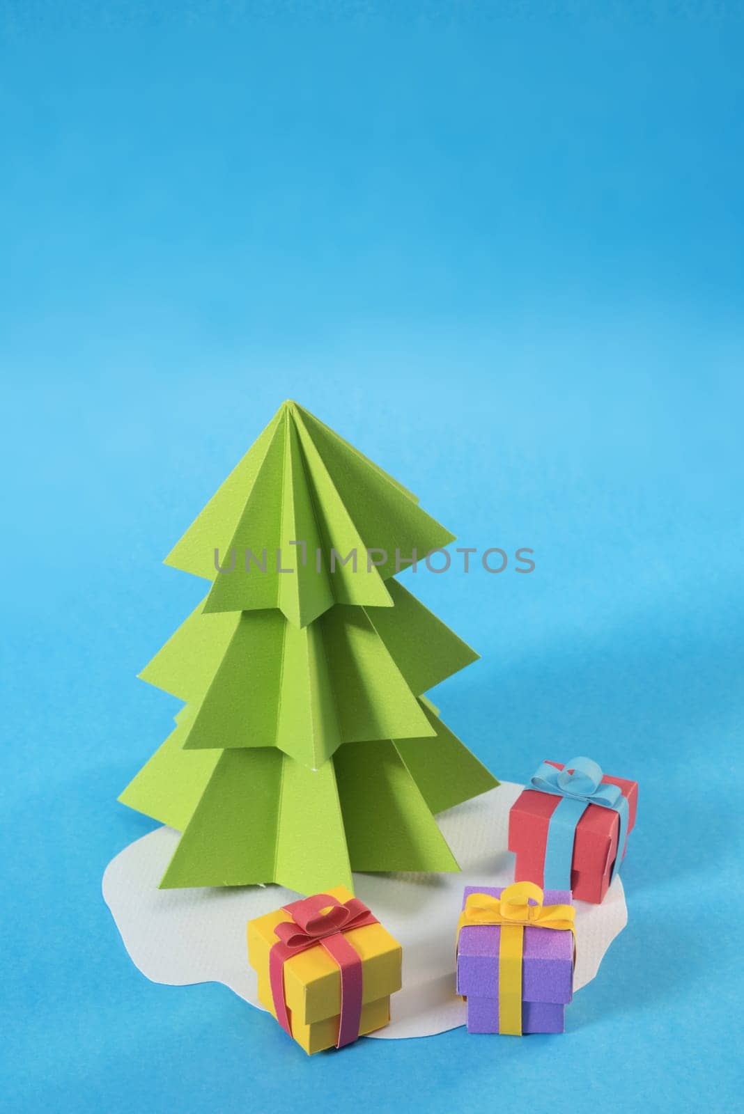 Christmas tree in paper cut handmade style with gift boxes on colorful blue background. Ideal for xmas greeting card, holiday poster or web.