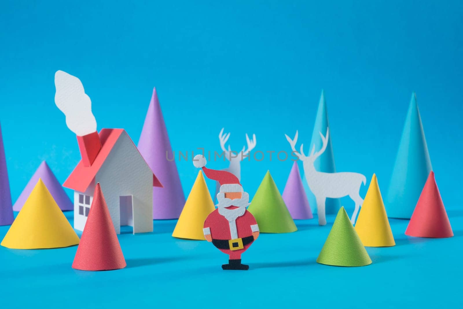 Christmas paper cut house with handmade santa and deers on colorful blue background. Ideal for xmas greeting card, holiday poster or web.