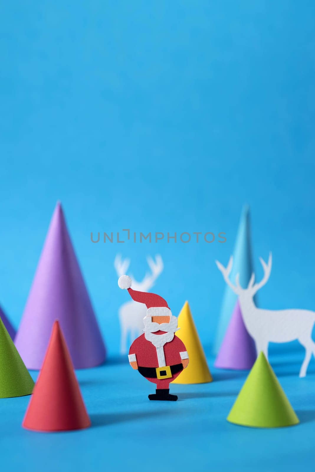 Christmas scene with handmade paper cut santa, deers and pine tree shapes, includes copy space. Ideal for holiday greeting card, poster or web.