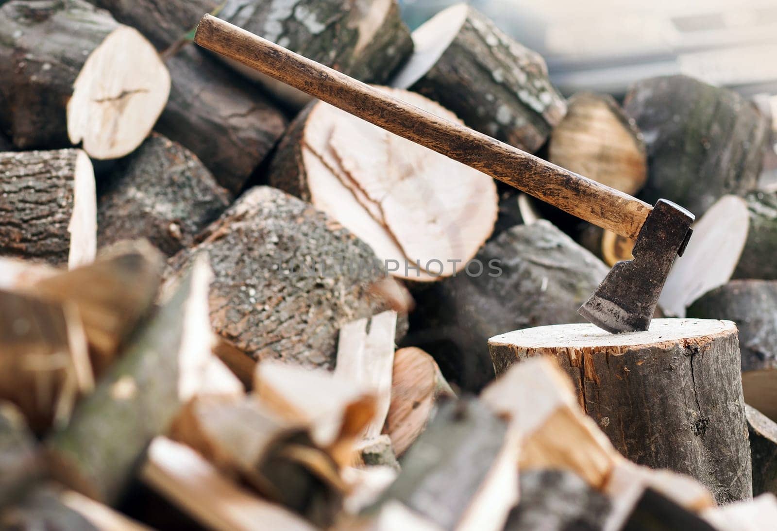 Axe stuck in a stump on a background of chopped firewood