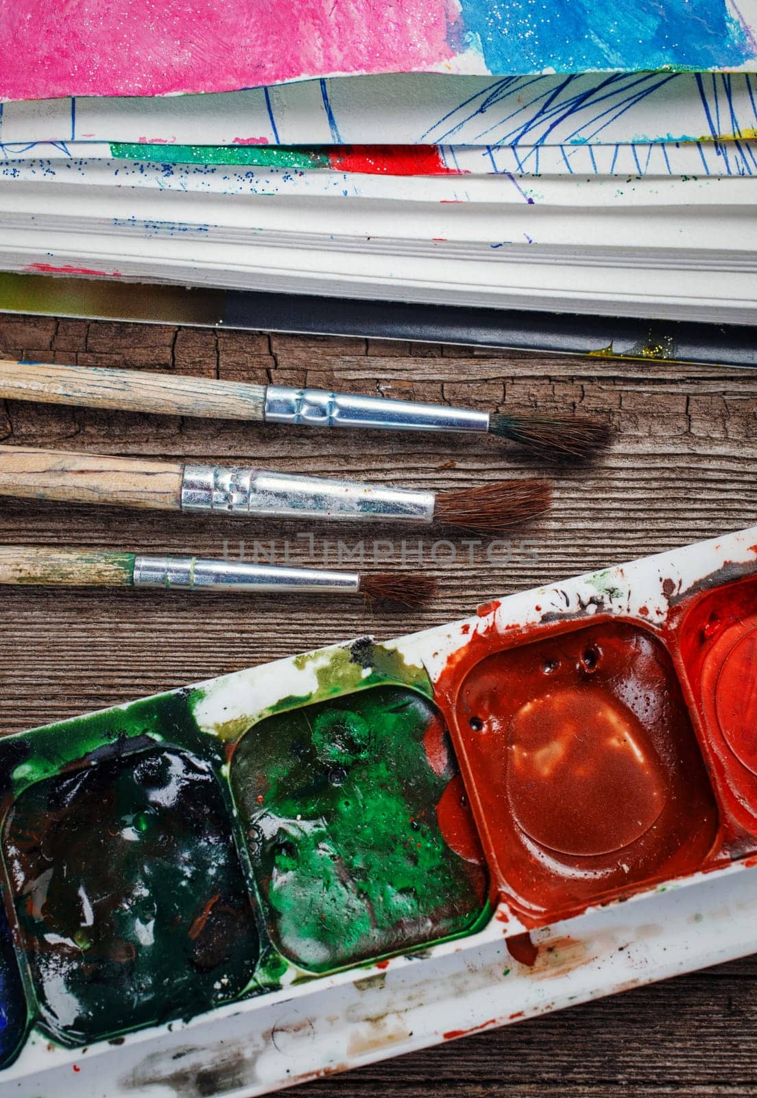 Paints and brushes on a wooden background closeup