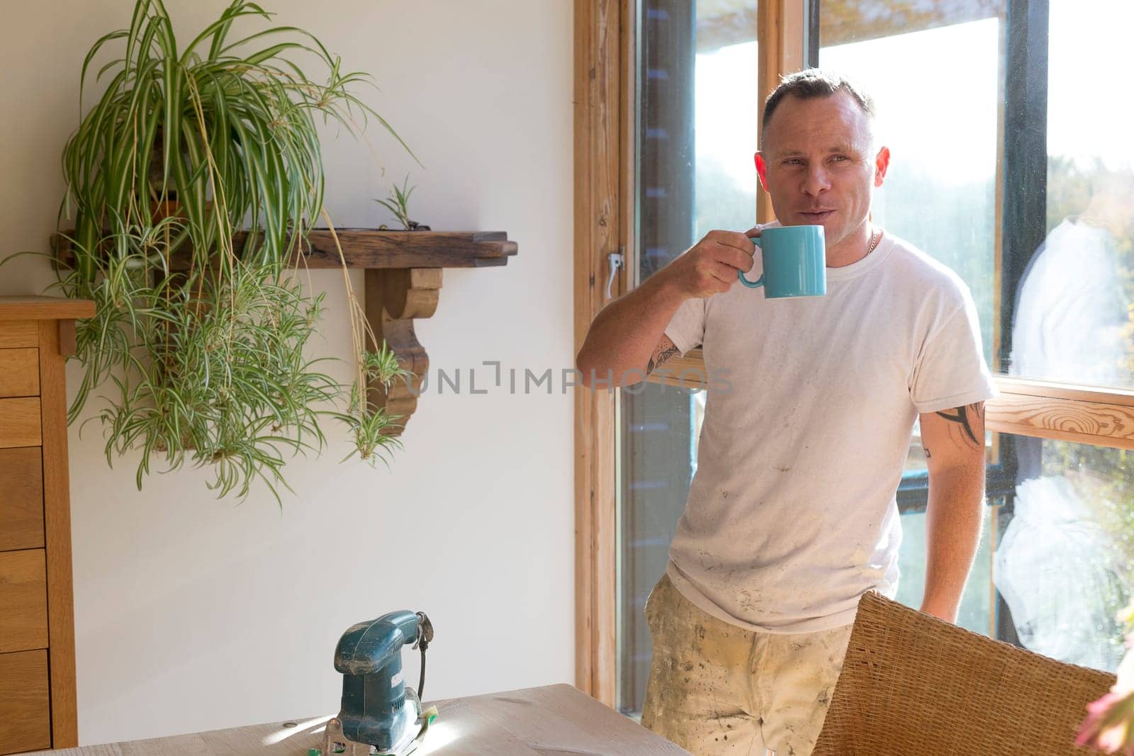 Wood joiner having a break from work and enjoying a cup of tea in the sunshine