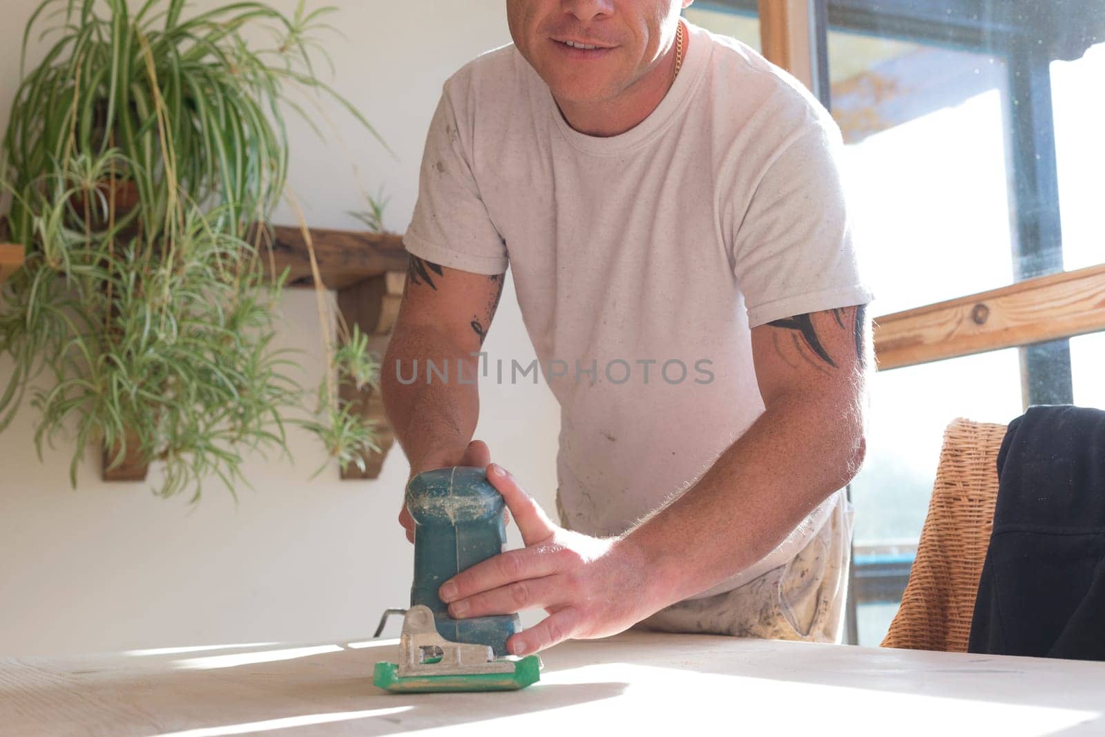Wood joiner using an electric sander to smoothen a table surface