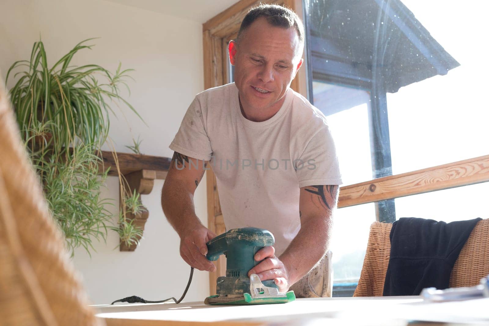 Wood joiner using an electric sander to smoothen a table surface
