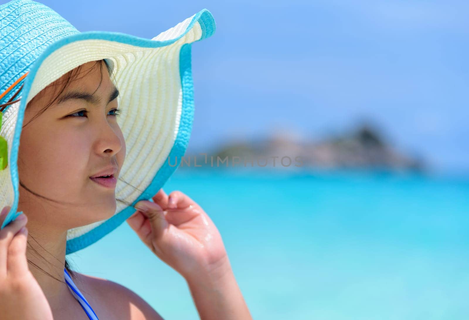 Face young woman wearing sun protection hat  is happy to see the beautiful nature of sea and beach under the summer sky at Koh Miang Island in Mu Ko Similan National Park, Phang Nga, Thailand
