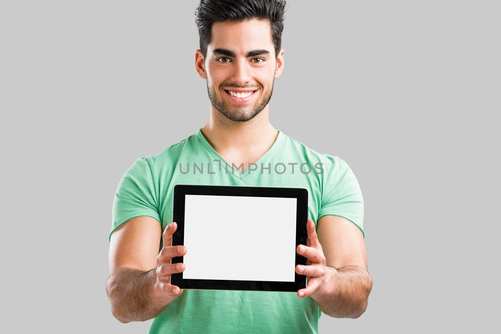 Handsome young man working with a tablet, isolated over gray background