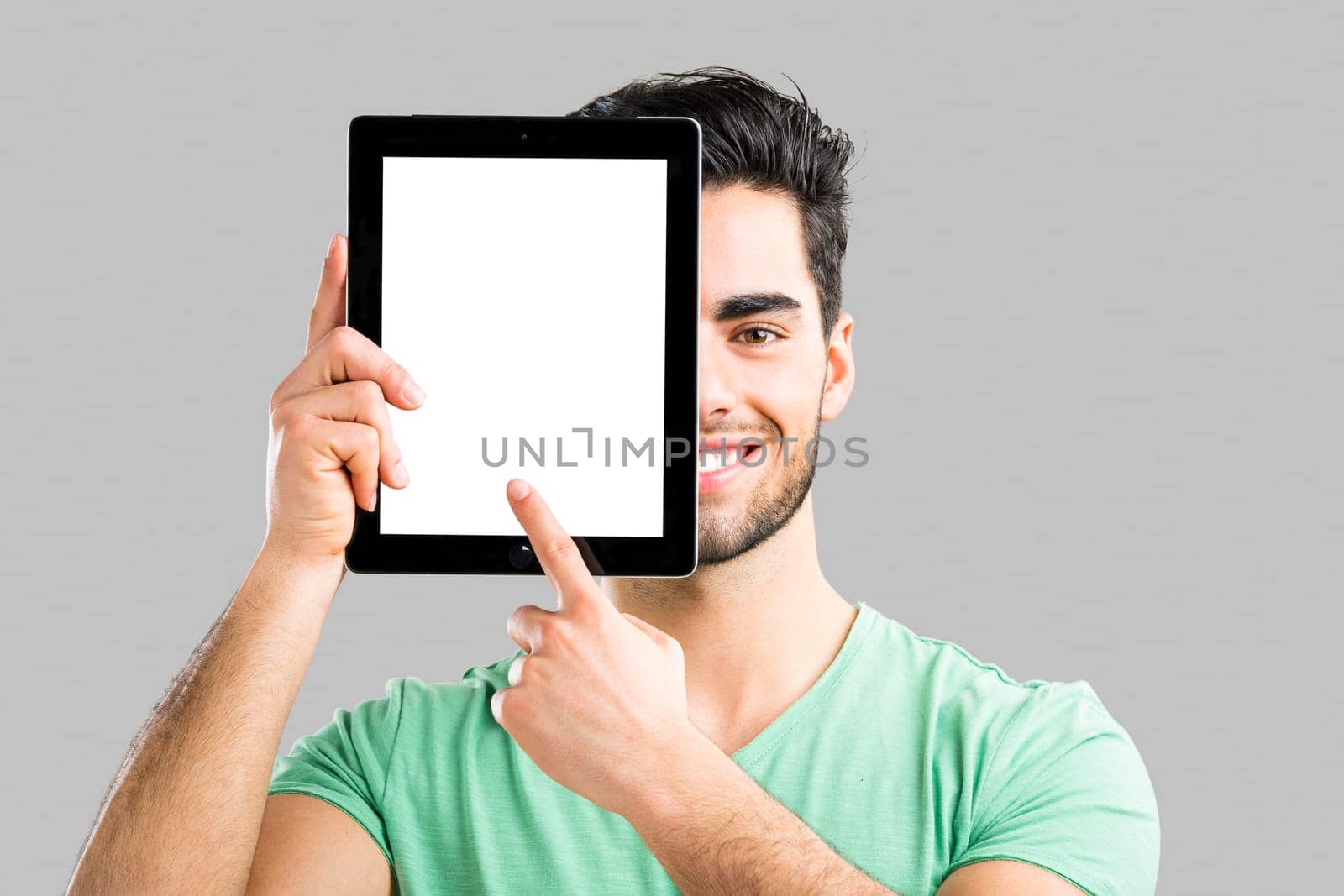 Handsome young man working with a tablet, isolated over gray background
