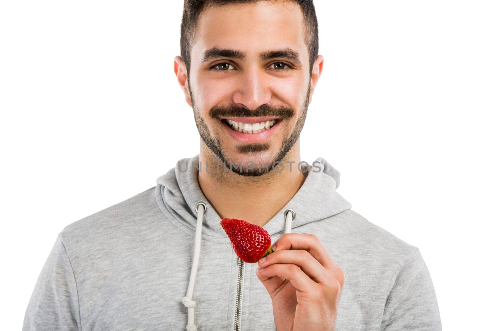 Happy young man eating a strawberry, isolated on white background