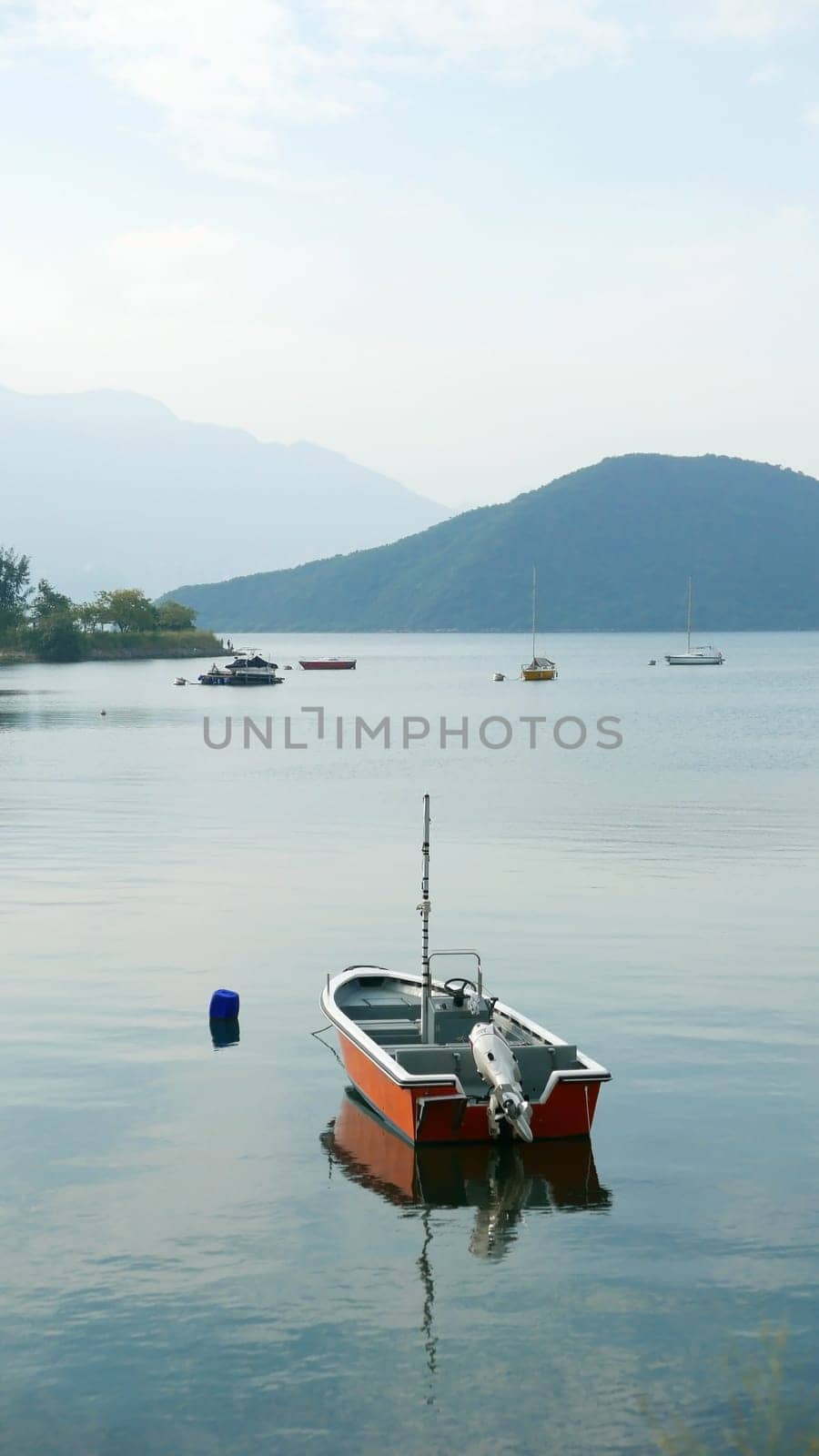 Red fishing boat on peaceful lake in day time