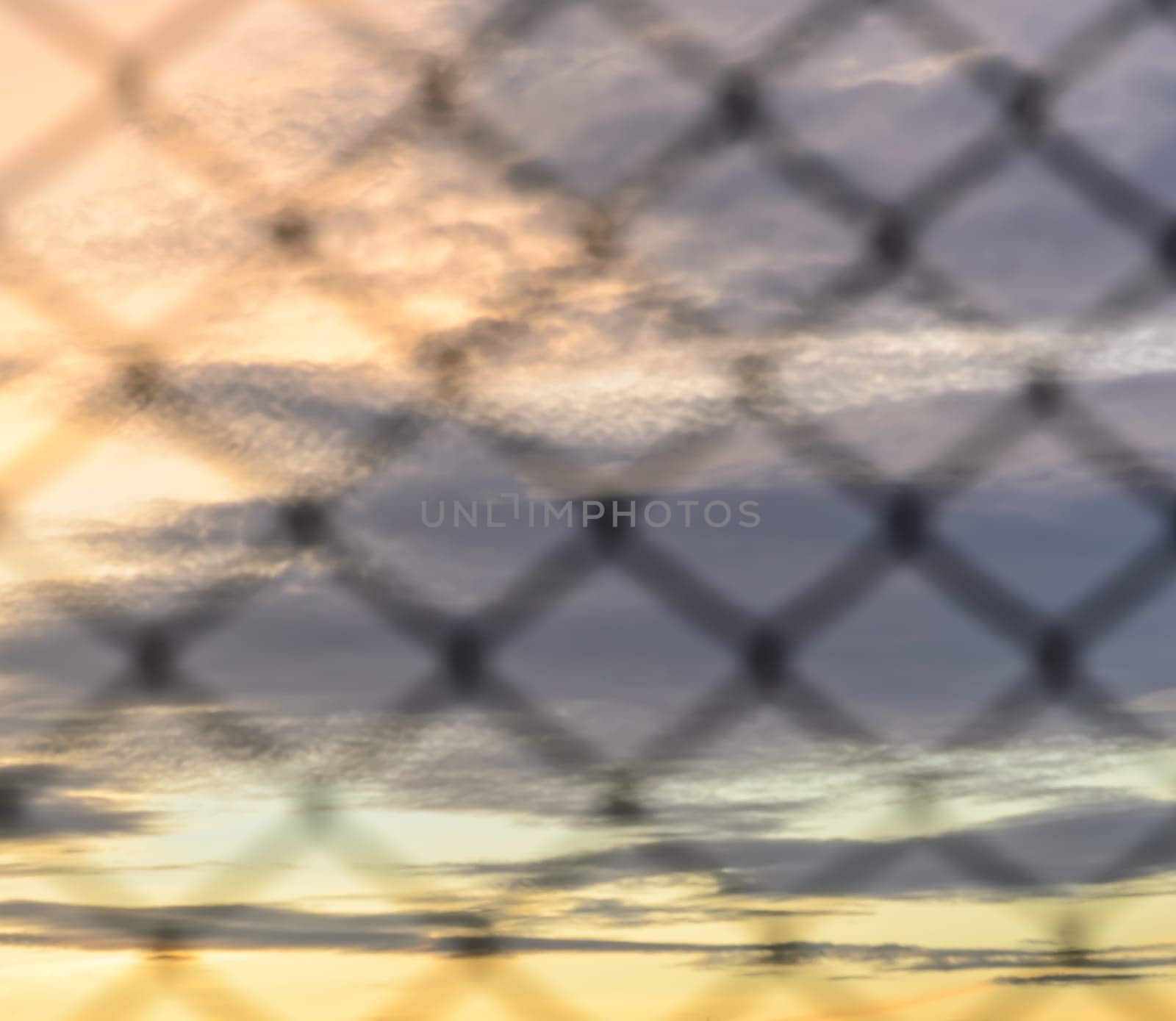 Sunset background with blurry wire mesh fence