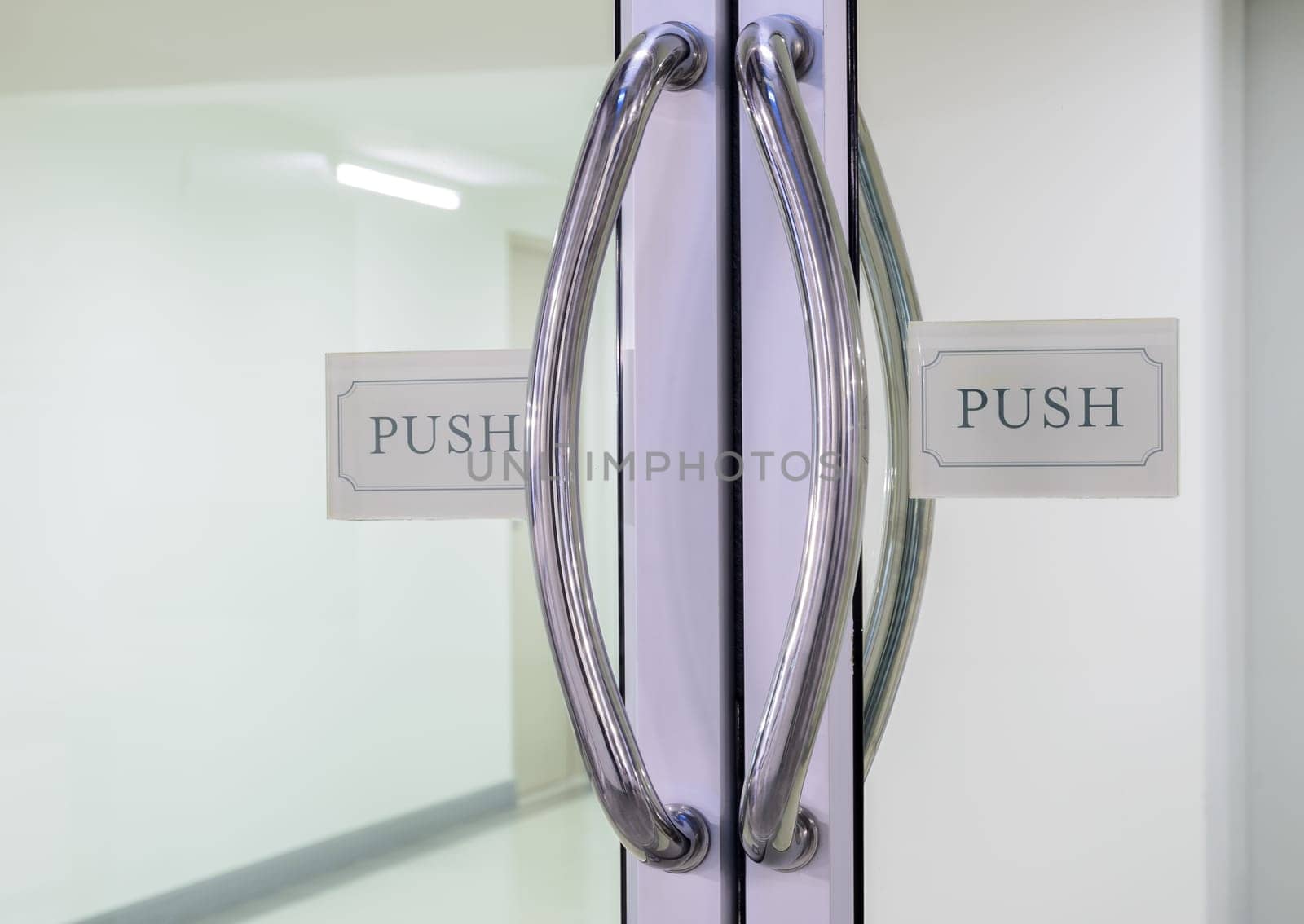 Glass door with chrome handles and push sign on door