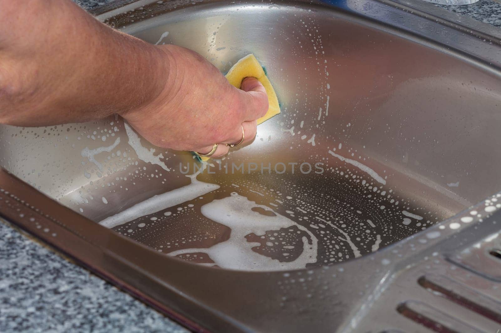 Cleaning a kitchen sink with yellow sponge... Cleaning a kitchen sink with yellow sponge