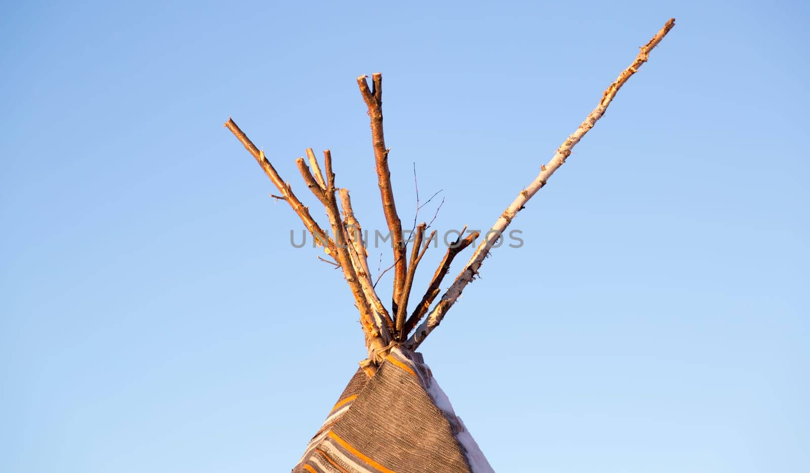 Top of a Tipi with a clear blue sky behind it.