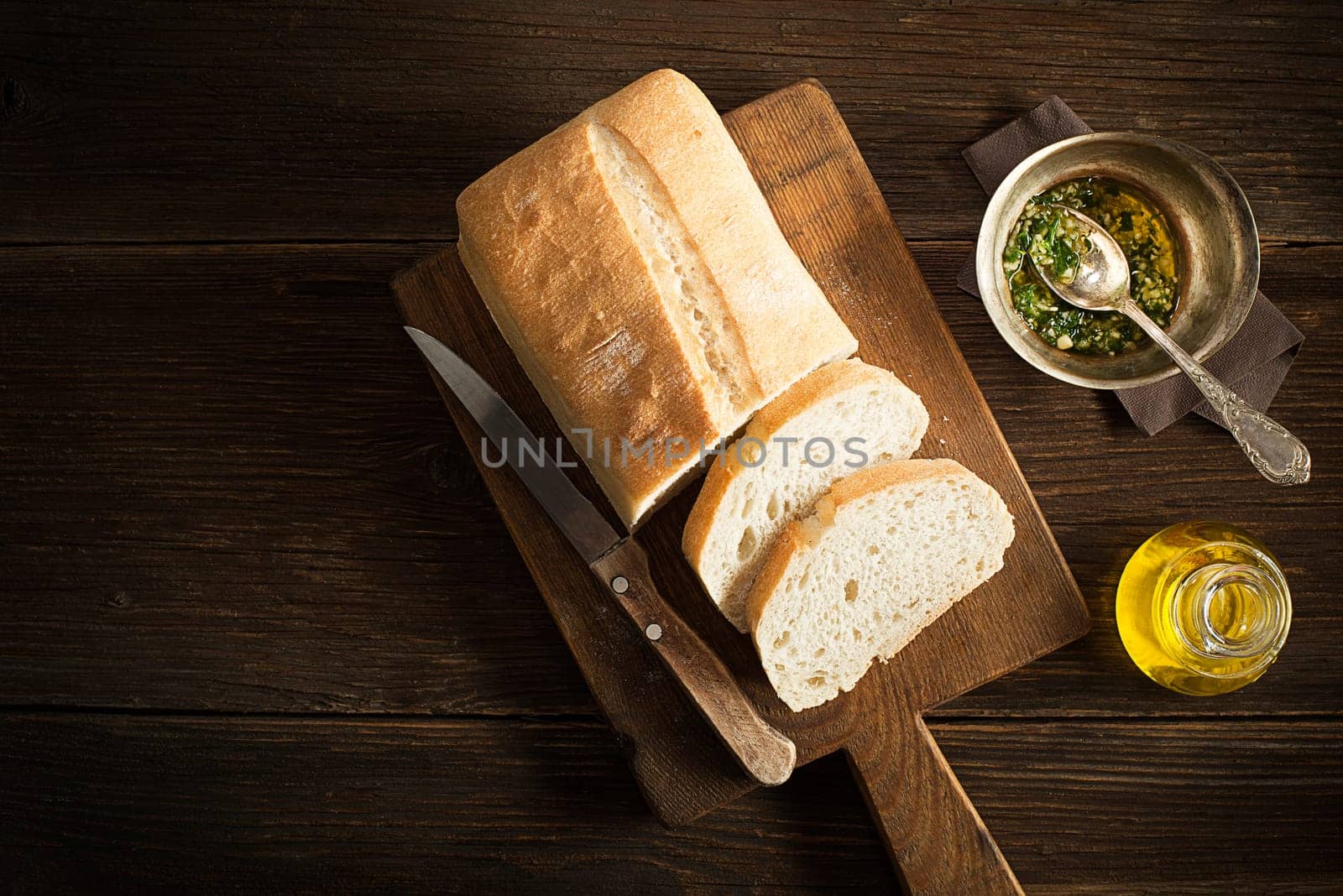 Bread with garlic and olive oil on wooden background.