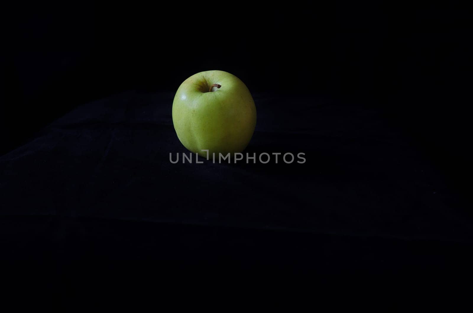 one green apple on a black background fresch and healty