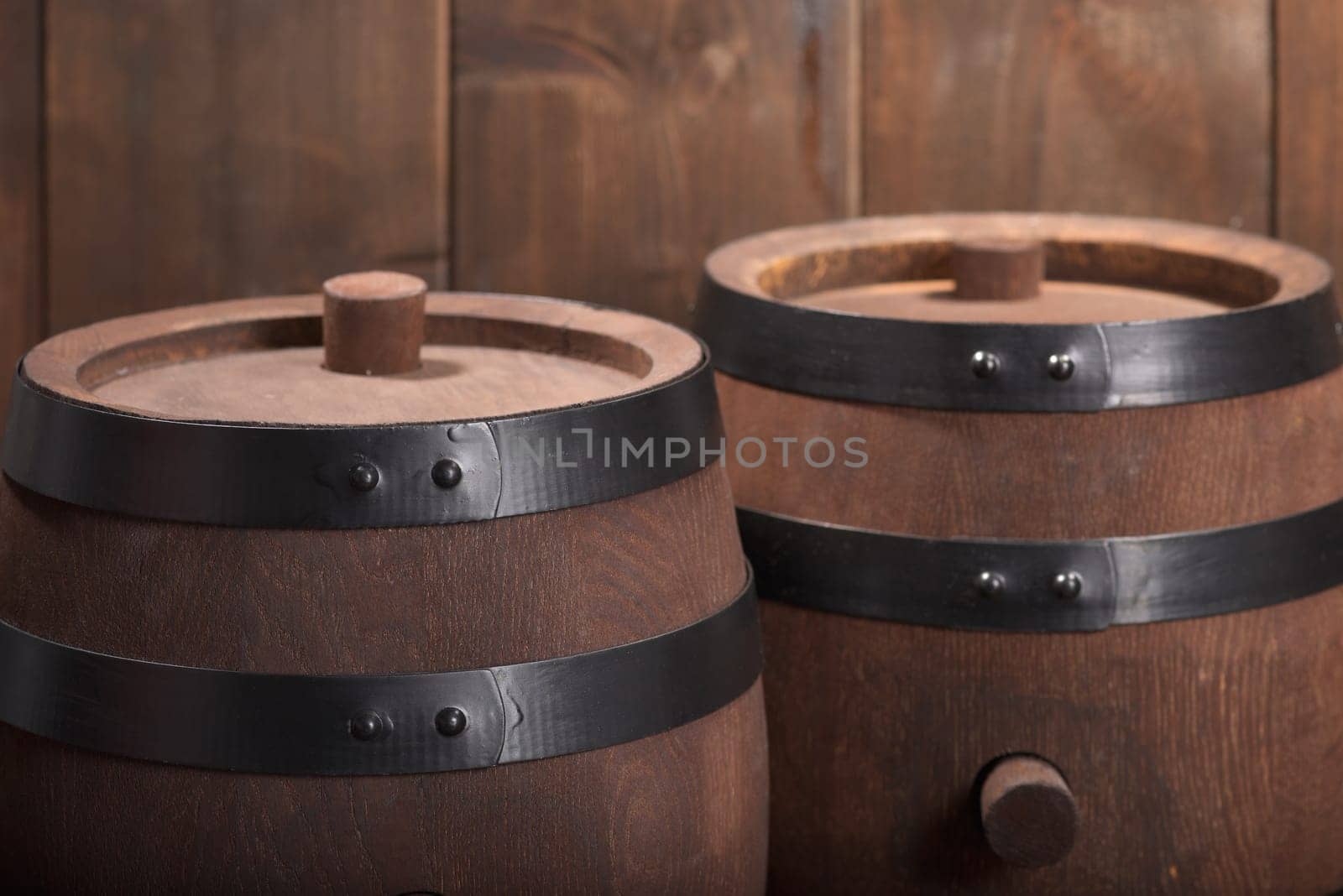 two old wooden barrels with wooden plugs on a dark wood background