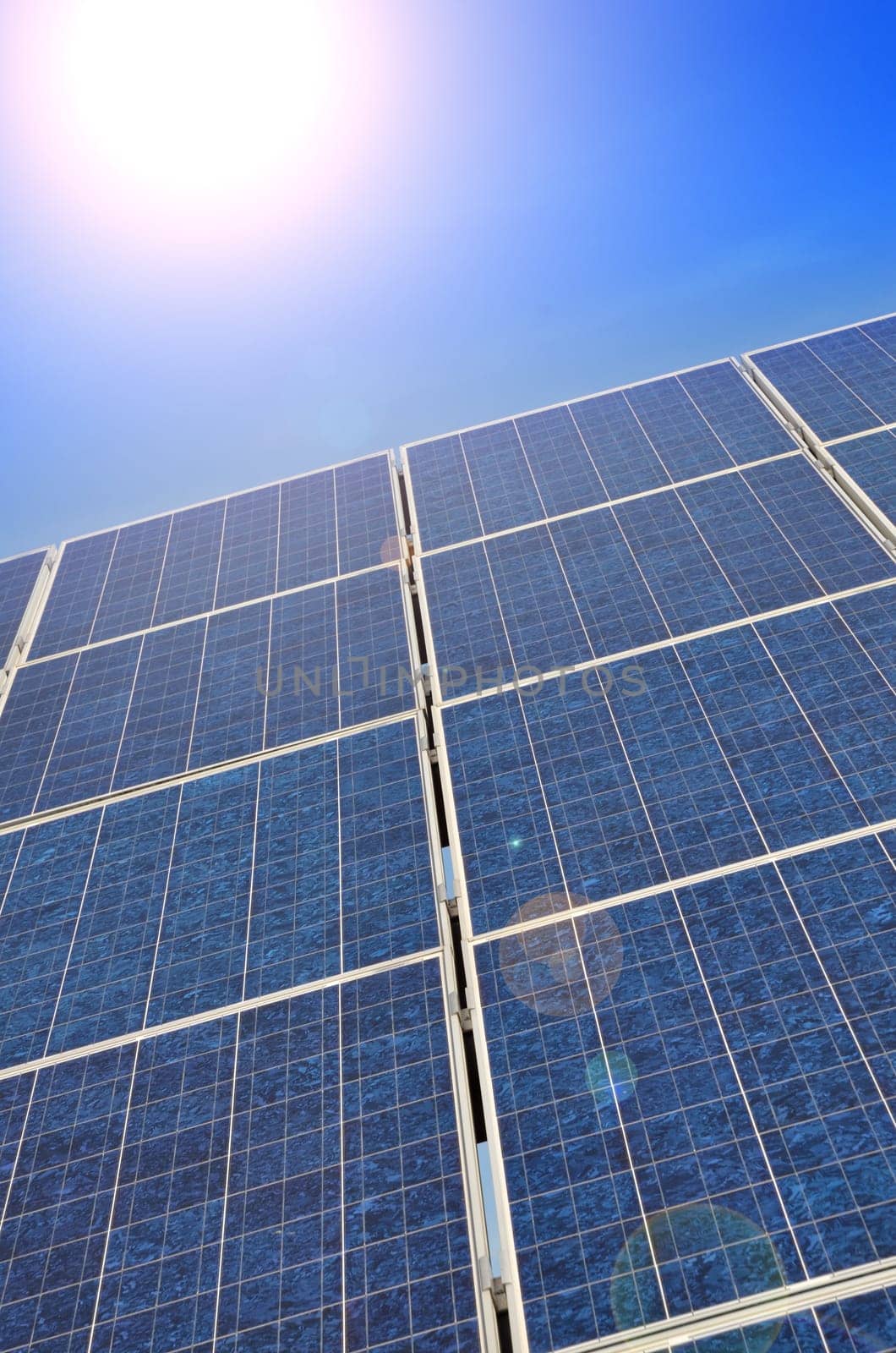 Solar panel with bright sun on a blue summer sky