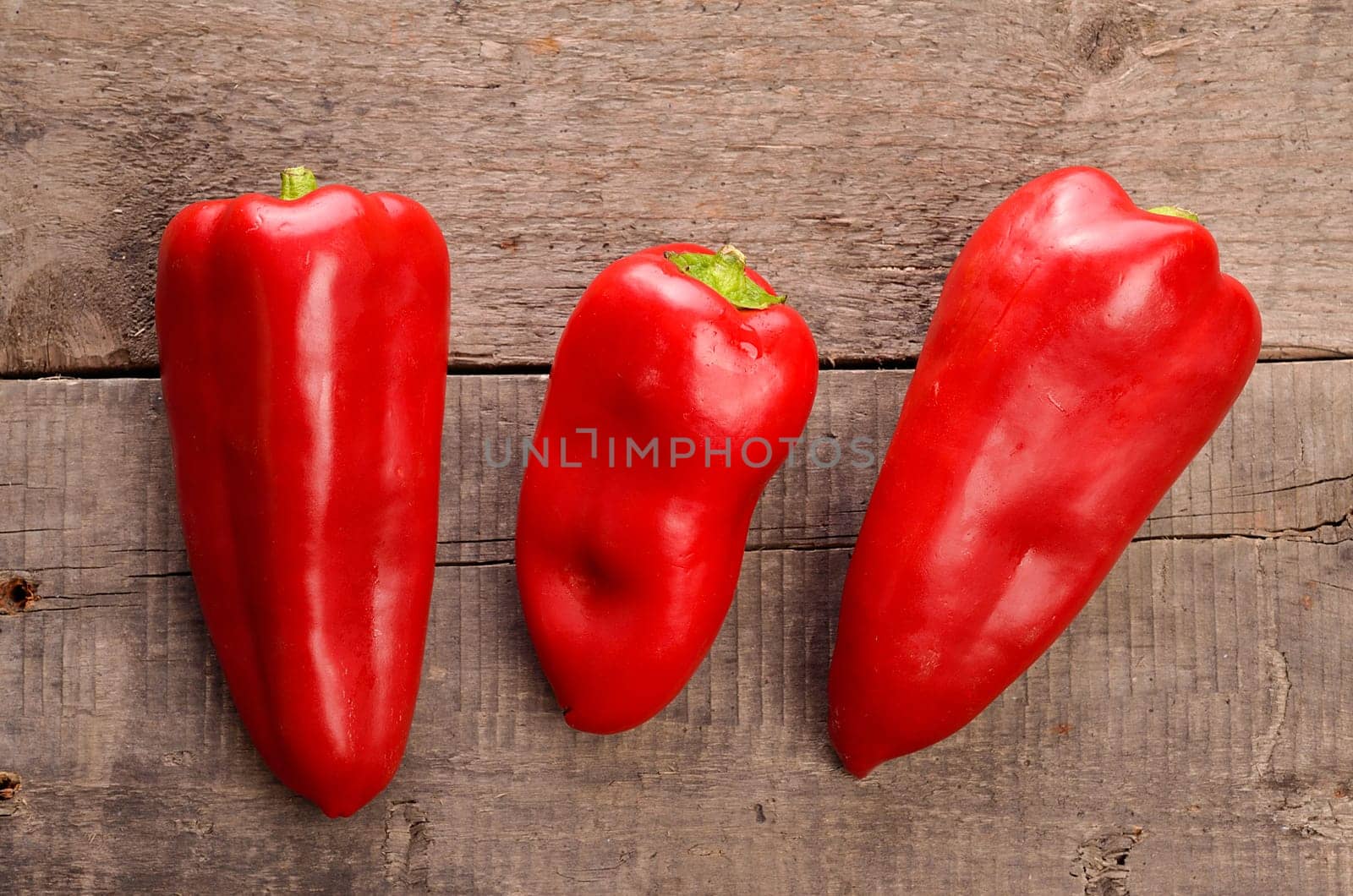 Three red fresh paprika on an old used barn wood