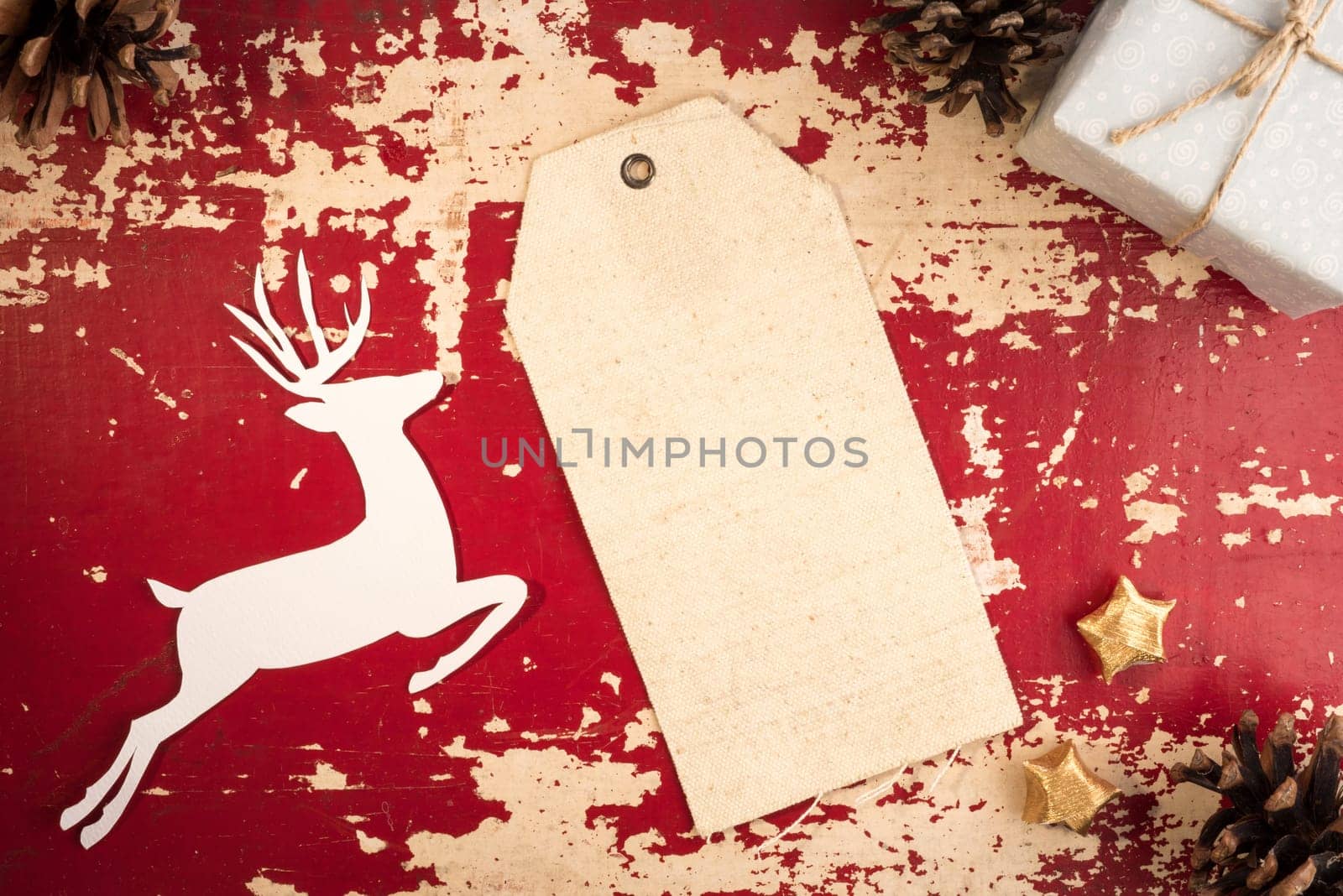 Merry Christmas vintage top view fabric hang tag label template with paper cut deer silhouette and holiday decoration elements on grunge wood background. Includes clipping path.
