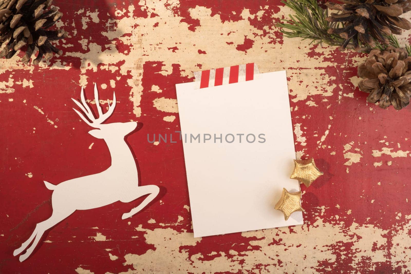 Hipster christmas holiday concept top view design, reindeer silhouette with pine cone forest decoration on grunge red wood background and empty paper note template. Includes clipping path.