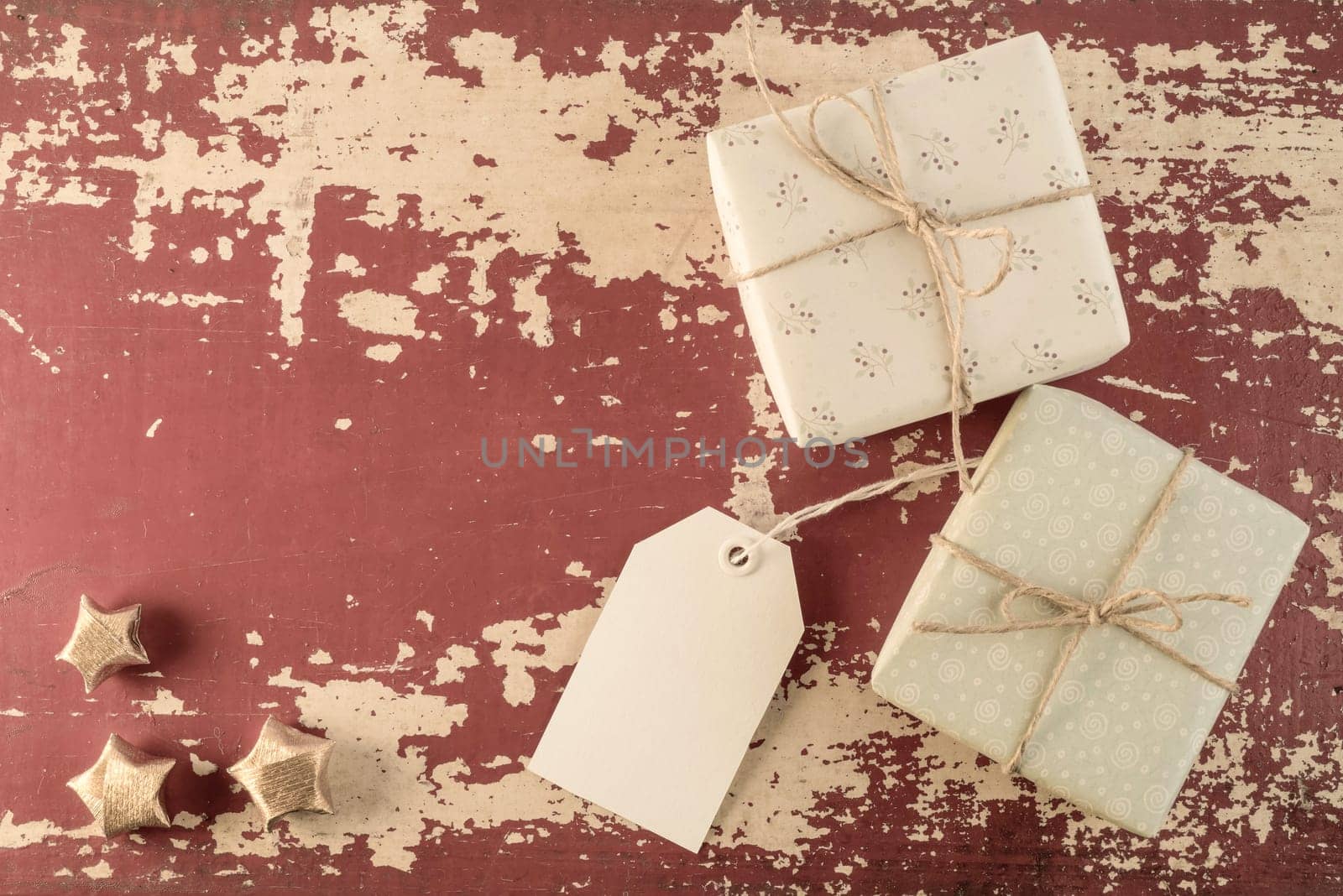 Holiday concept composition, top view vintage gift boxes with empty label template and paper gold stars on grunge wood texture background. Includes clipping path for tag.