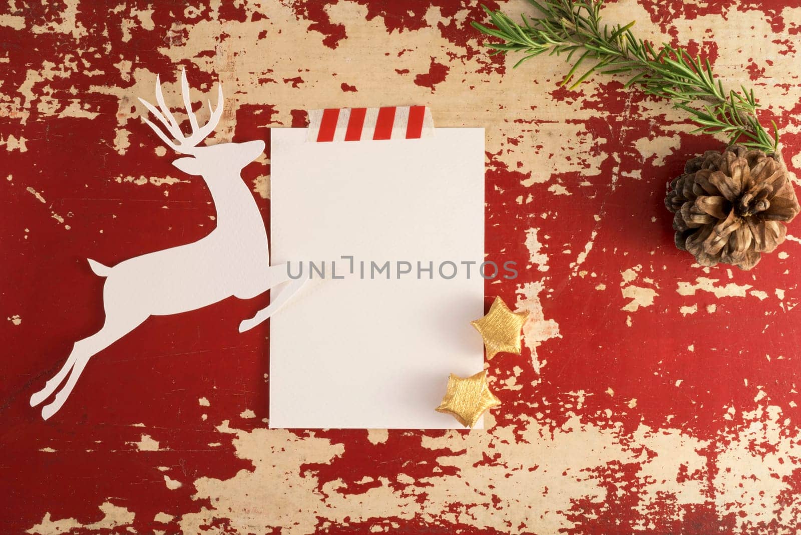 Christmas holiday concept top view composition template.  Reindeer silhouette and winter decoration on red grunge wood background. Paper note with copy space, clipping path.
