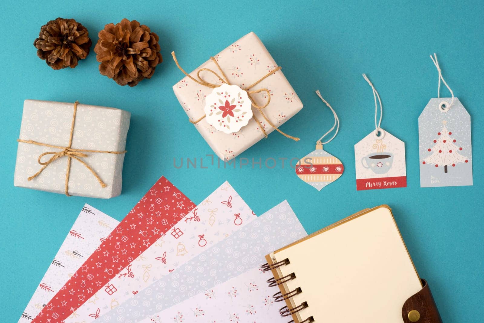 Merry Christmas top view composition with stationery set template. Spiral notebook with copy space and wrapping paper stack, vintage gift boxes and holiday decoration.   .