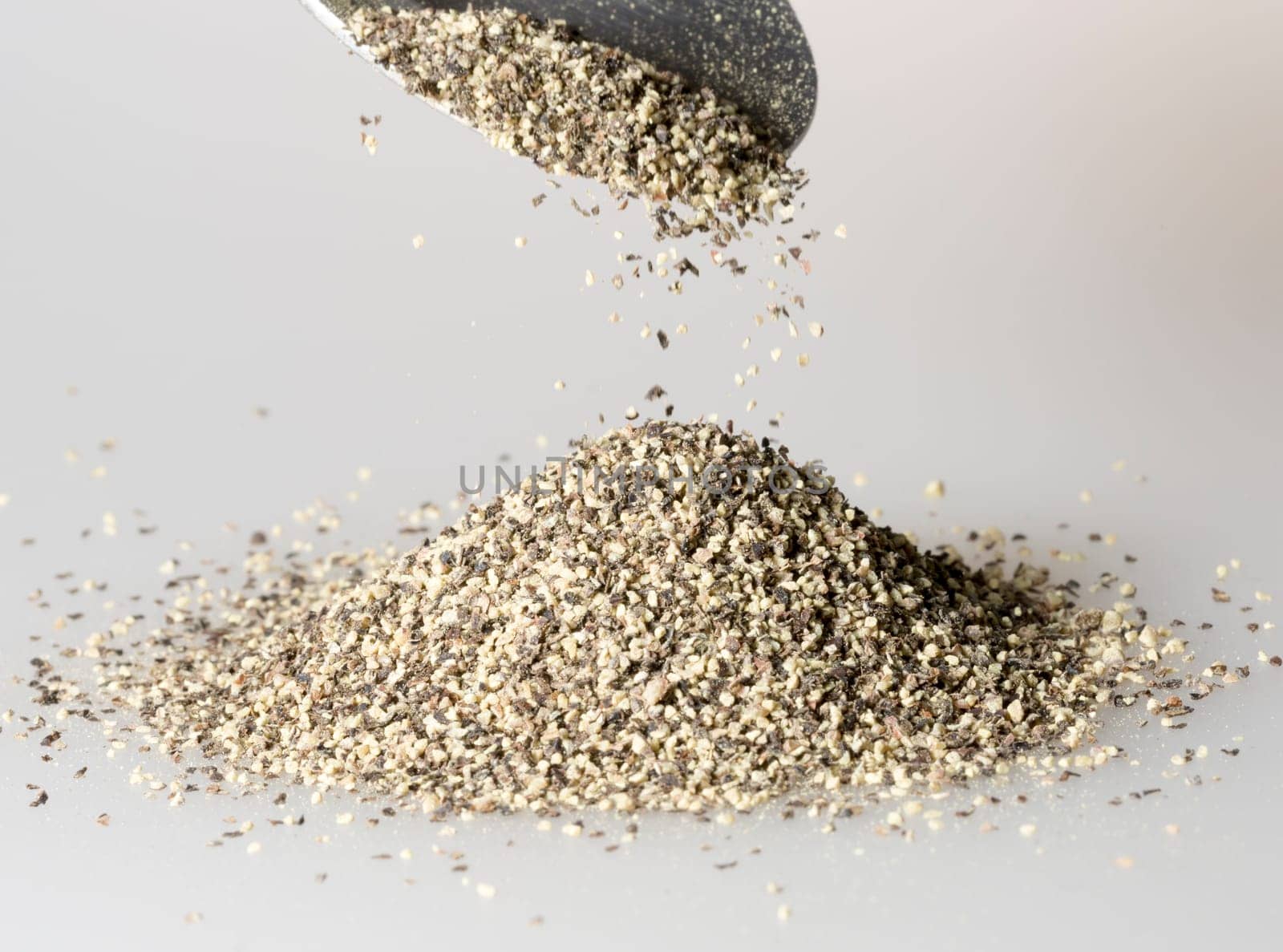 Black Pepper Falling from tablespoon close up.